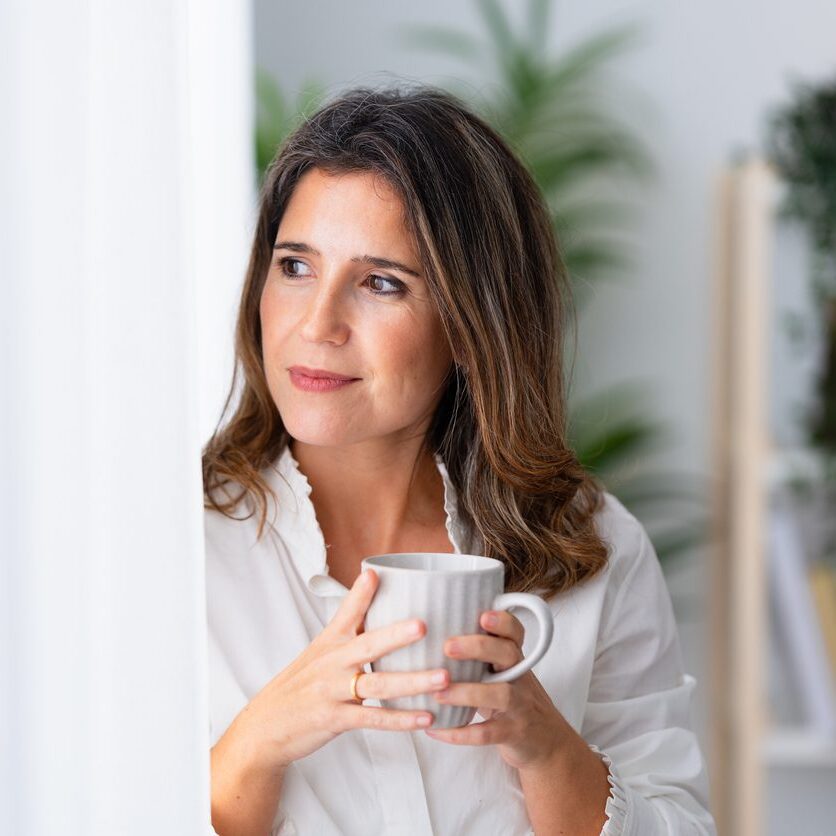 woman looking out the window holding a mug